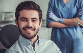 Man smiling in dental chair after tooth colored fillings procedure