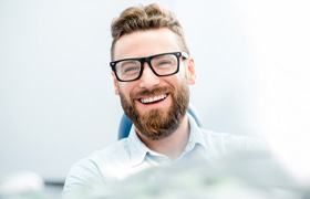 man smiling while sitting in dental chair 