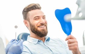 Man looking at smile after dental crown restoration