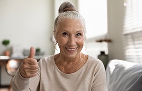 older woman smiling and giving thumbs up 
