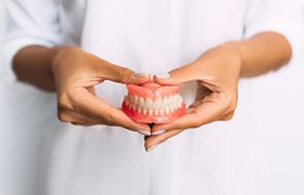 a dentist holding a pair of dentures