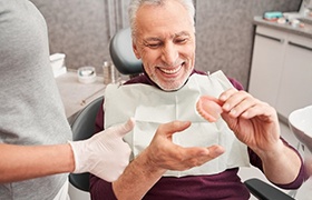a patient smiling while holding their new dentures
