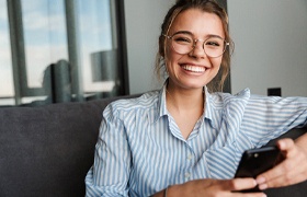 a person smiling and using cellphone after dental implant failure and salvage