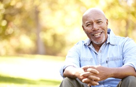 Man with dental implant dentures in DeLand, FL sitting outside