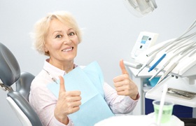 Senior female patient giving thumbs up after receiving dental implant dentures in DeLand, FL