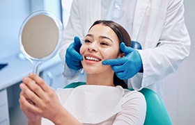 Female patient smiling in the mirror at the dentist’s office