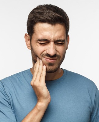 Man squinting eyes touching sore jaw with four fingers