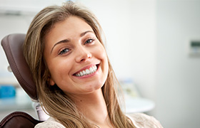 Smiling woman while receiving dental services