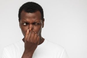 Man covering nose after smelling bad breath
