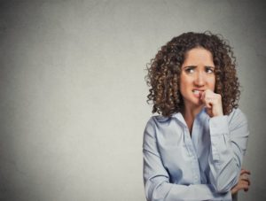 Woman with dental implants worriedly bites her fingernails