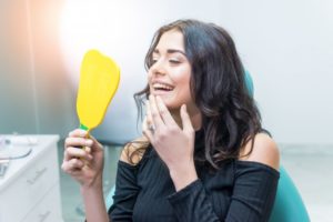 woman seeing her new smile after getting cosmetic dental treatments 