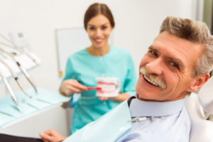 Elderly man sitting in dentist chair smiling