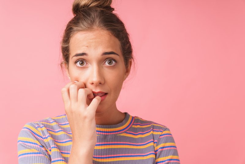 Young woman chewing her nails.