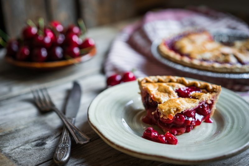 A slice of cherry pie on a dining room table.
