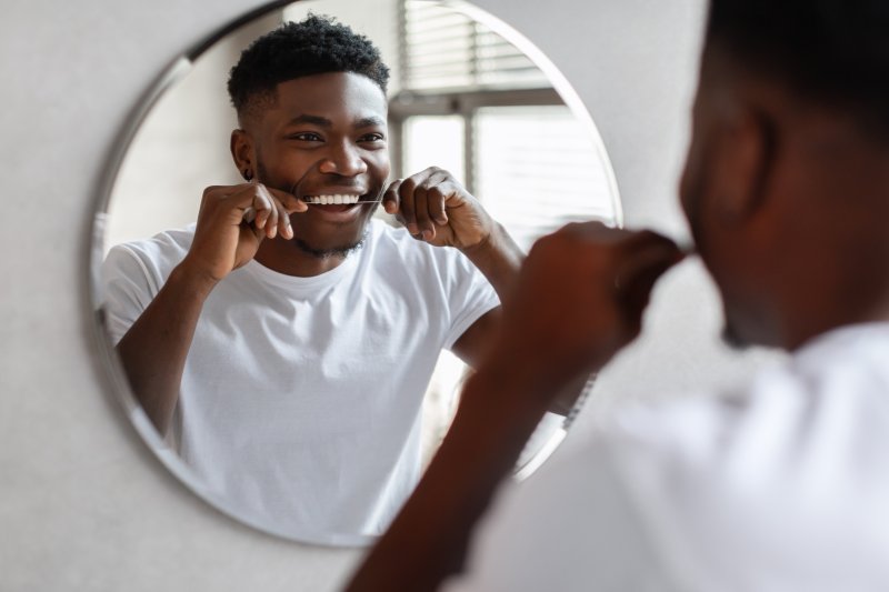 Man flossing between his dental veneers to keep them healthy