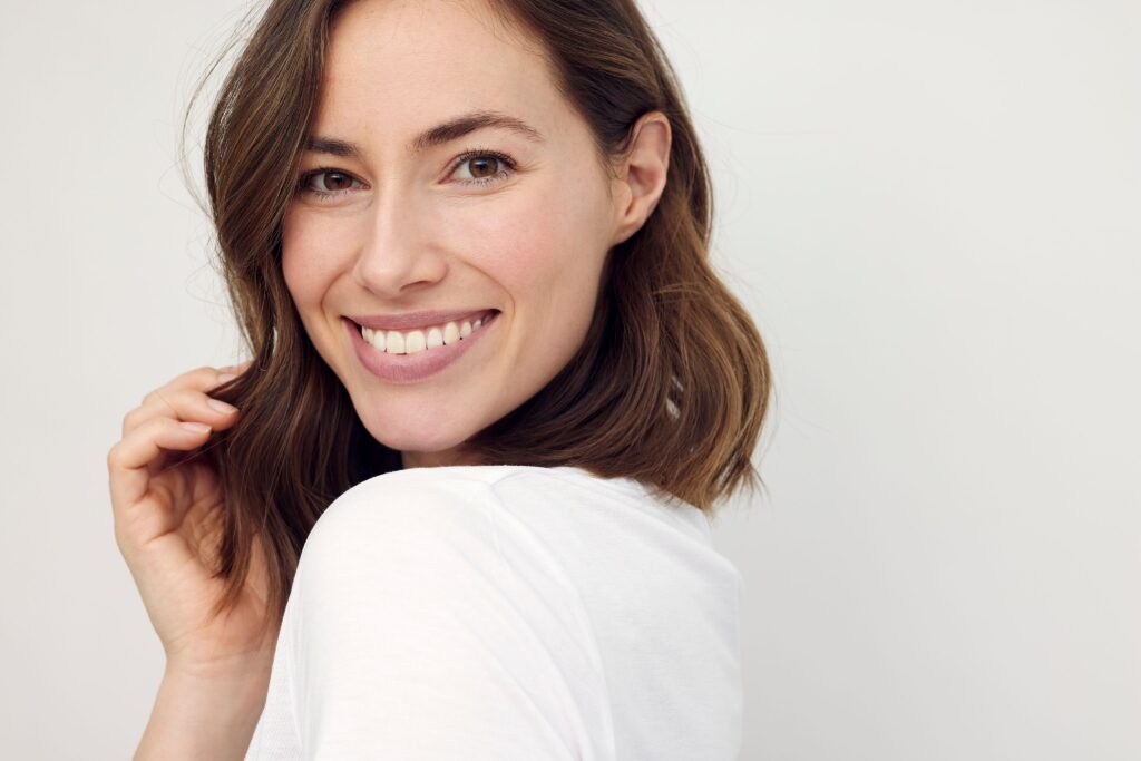 Woman with brown hair looking over shoulder smiling
