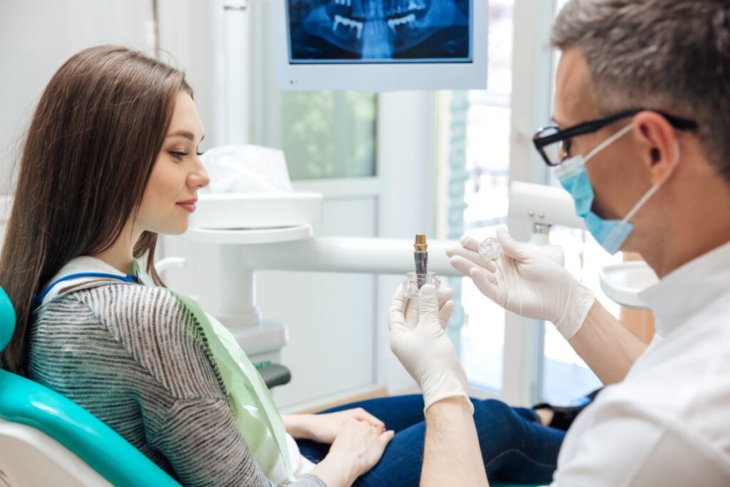 A dentist showing a patient a dental implant model